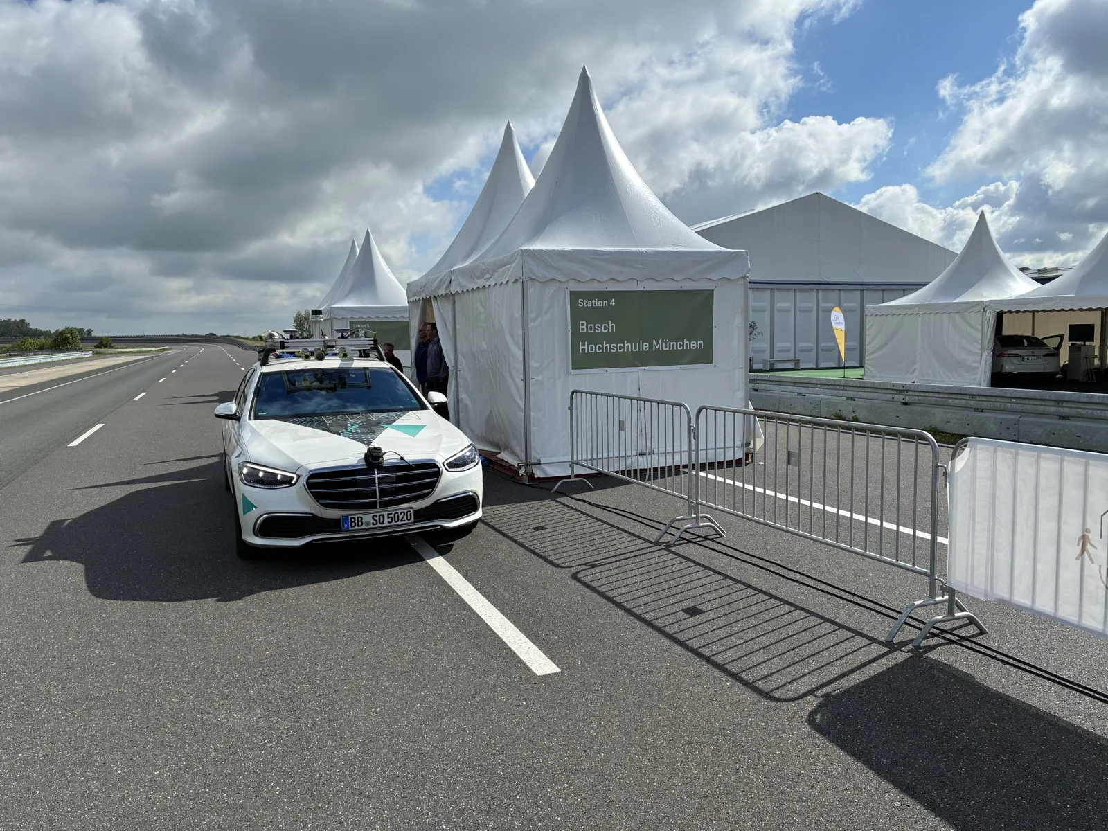 The test vehicle driving past the demonstration tents